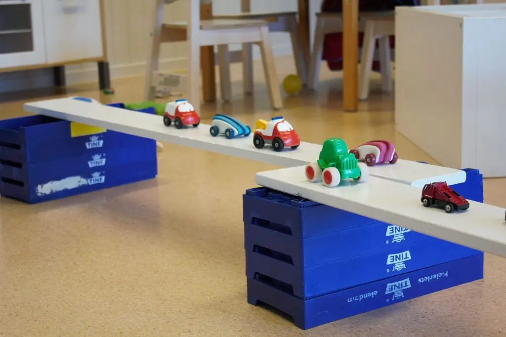En bilbane inne som er laget med melkekasser og planker.